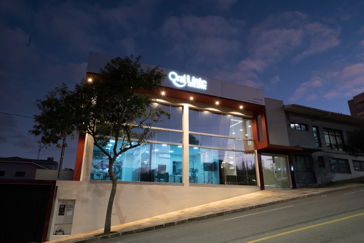 Fachada iluminada da Oral Unic Flores da Cunha ao anoitecer